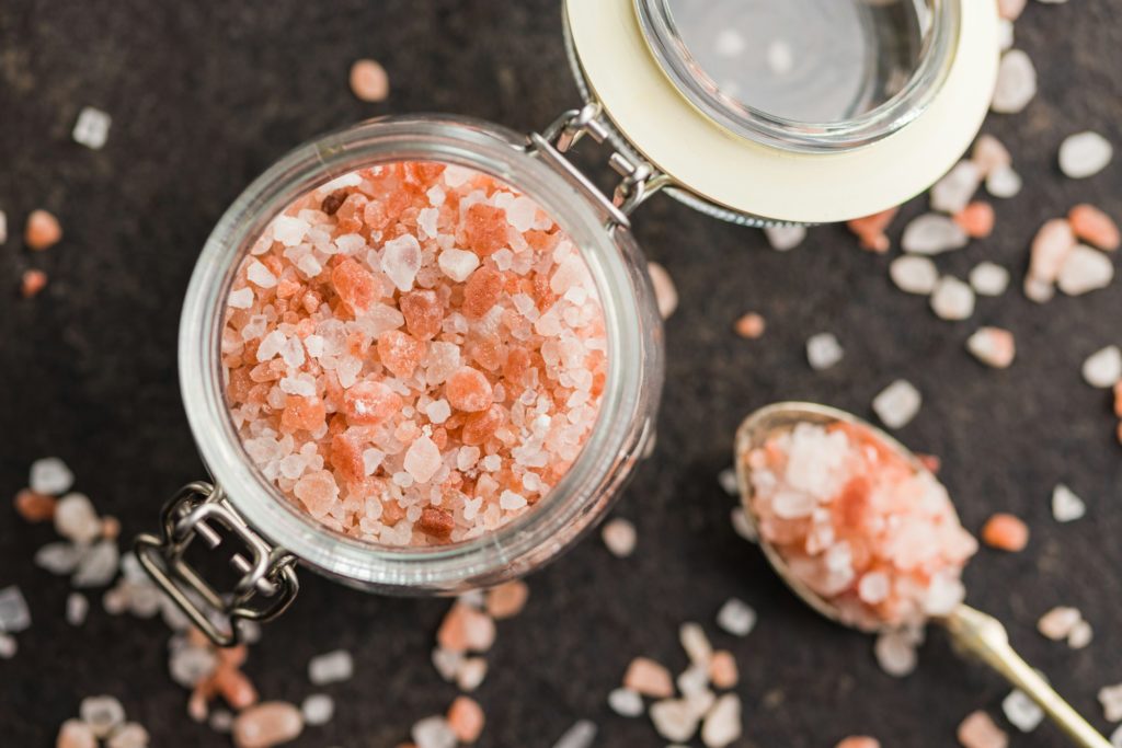 Pink himalayan salt in jar on black table. Top view.